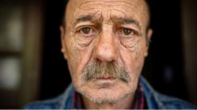 Man with wrinkled face looks into camera